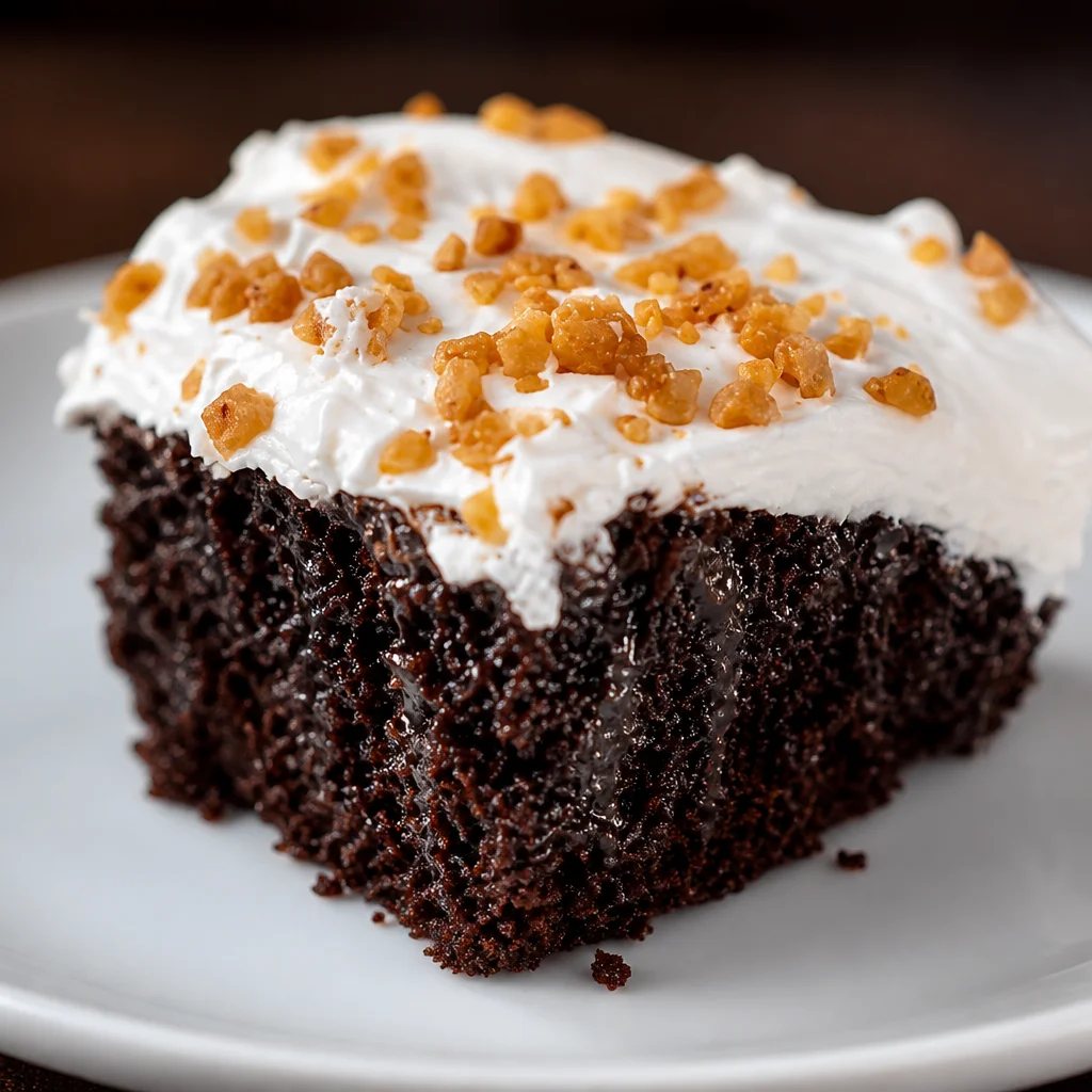 Delicious Hot Fudge Chocolate Poke Cake topped with whipped cream and chocolate fudge sauce.