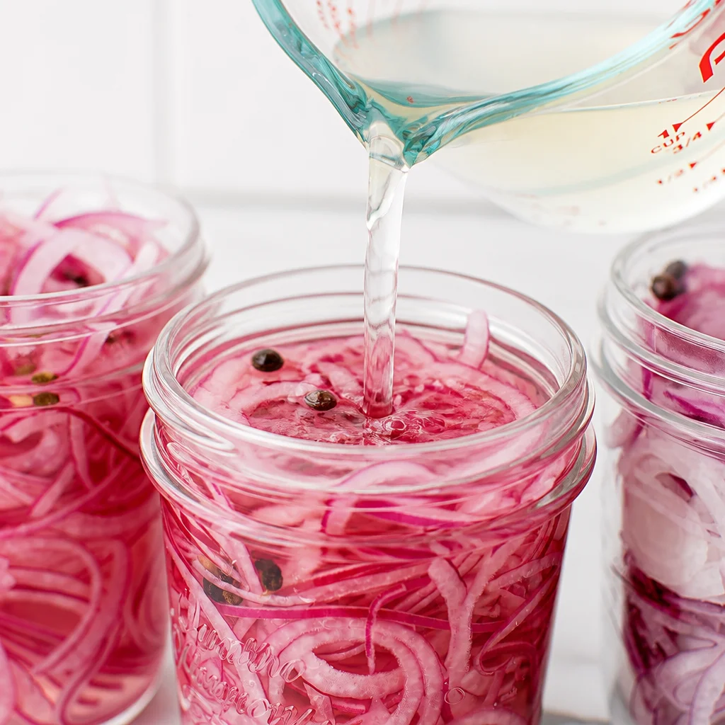 Pickled red onions in a jar with vibrant colors, ready to enhance your meals.